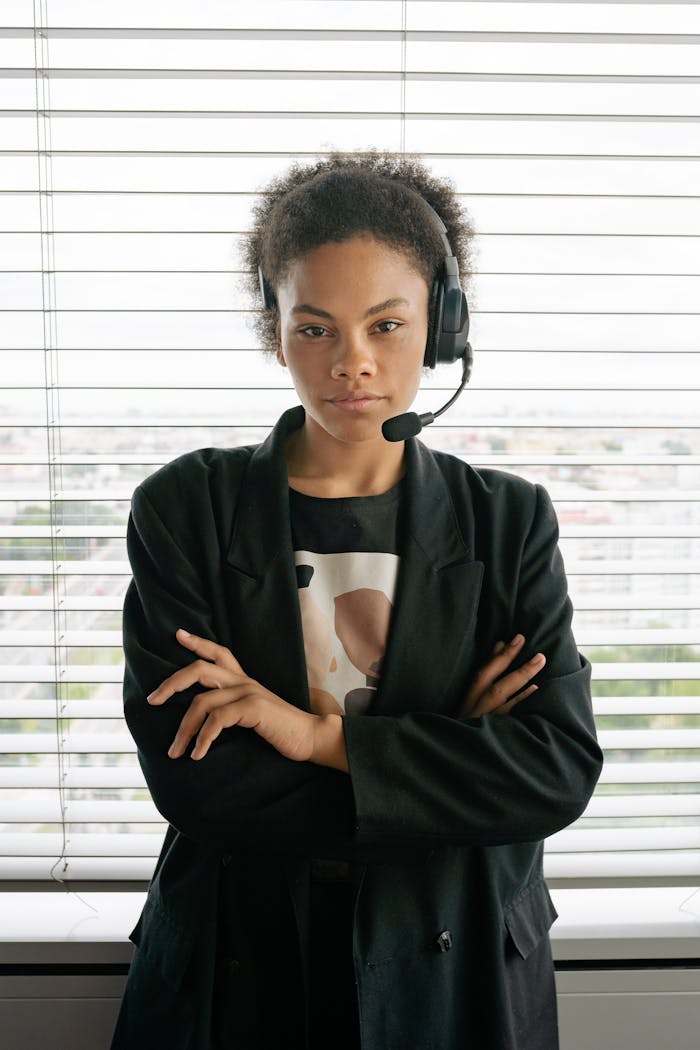 African American woman in a blazer wearing a headset, posing confidently in an office setting.